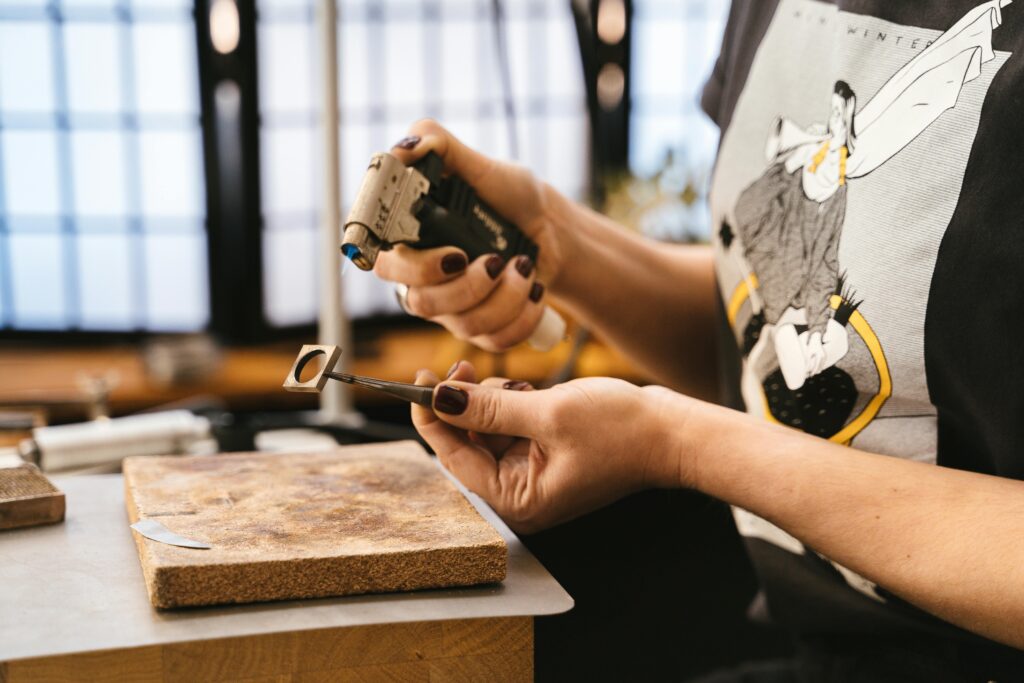 Close-up of artisan crafting jewelry using tools in a workshop setting.